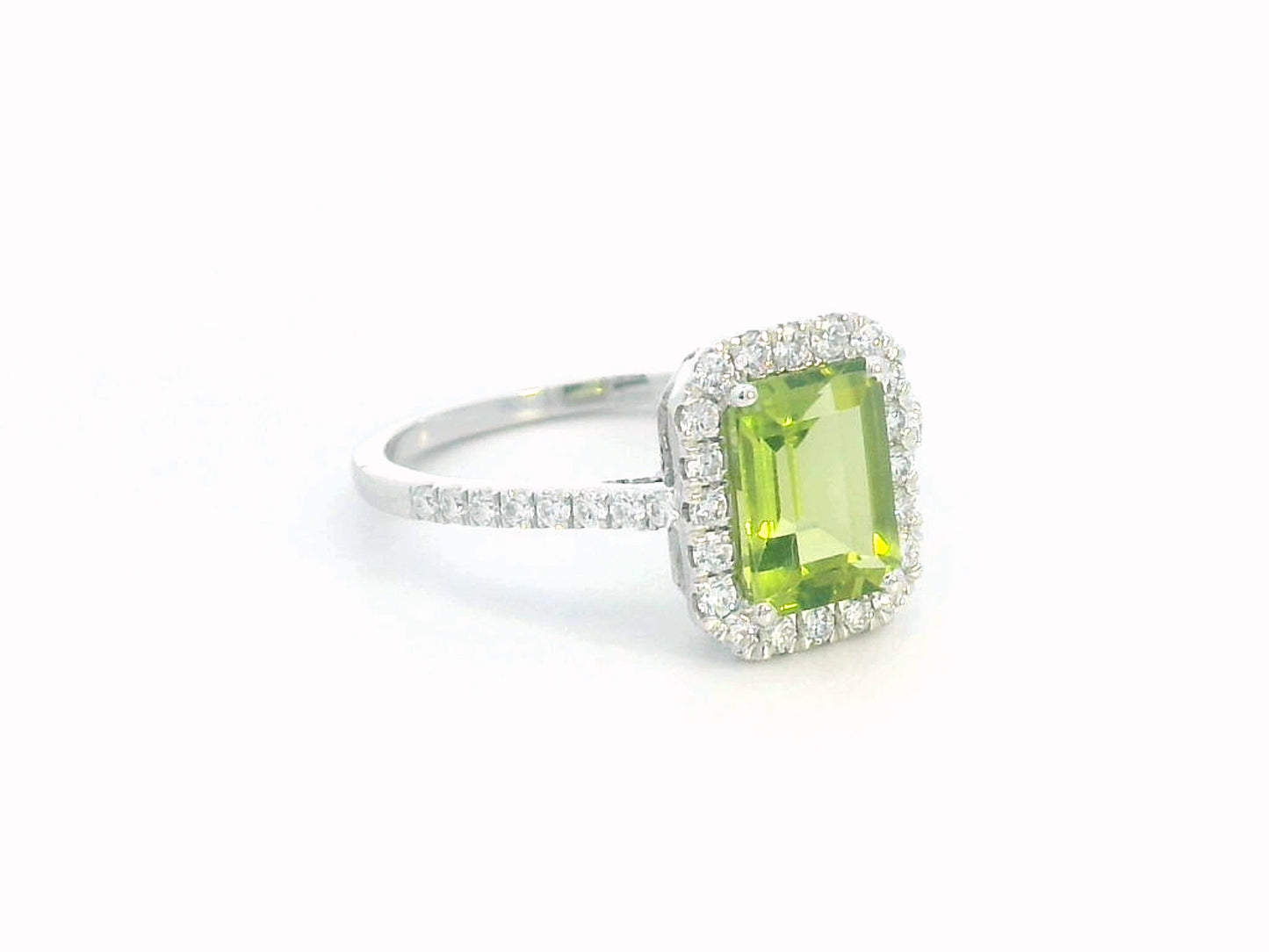 18K white gold emerald-cut Peridot ring with 0.35ct diamond halo, featuring 1.58ct Peridot centerpiece.