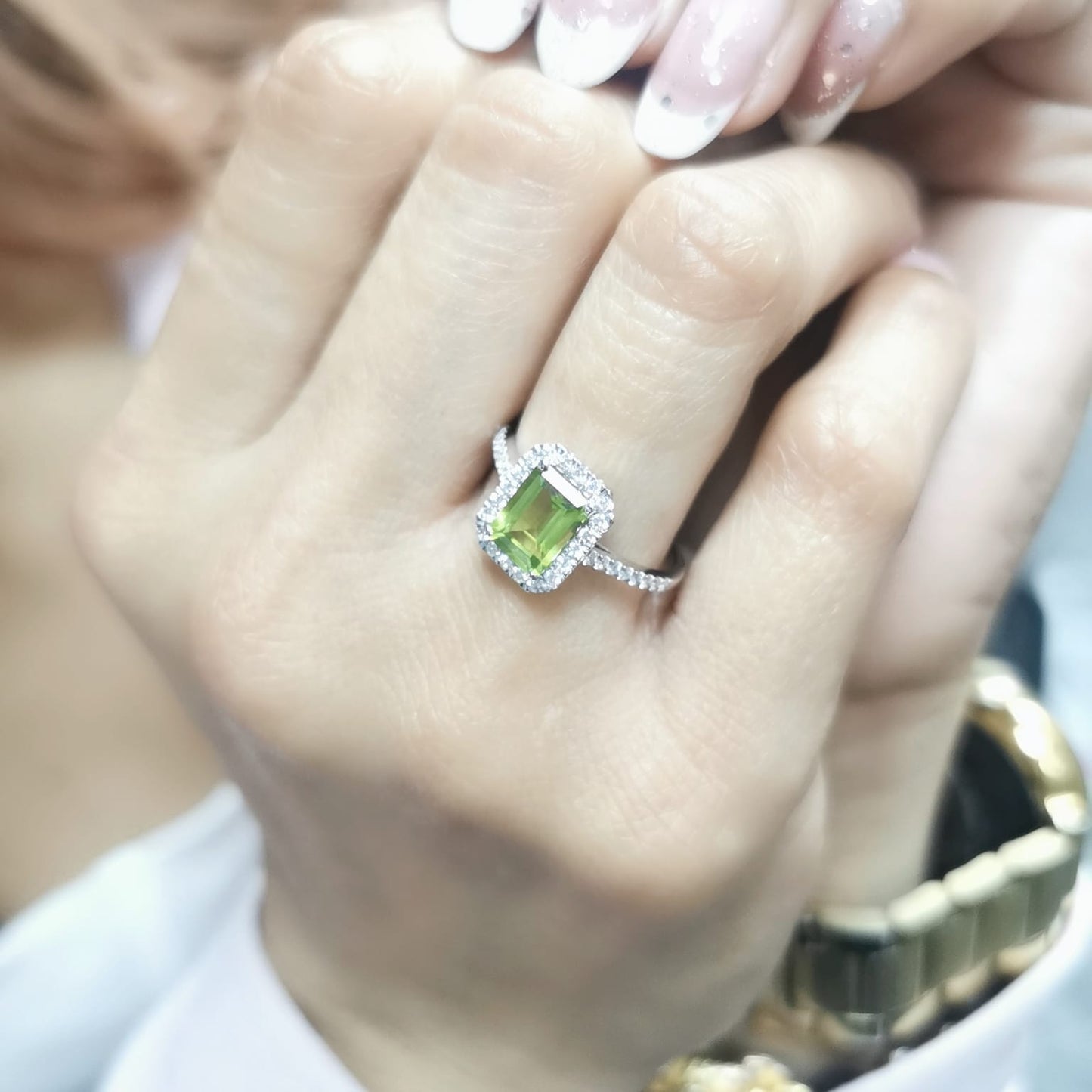 18K white gold emerald-cut Peridot ring with 0.35ct diamond halo, featuring 1.58ct Peridot centerpiece.