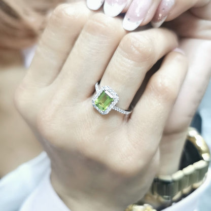 18K white gold emerald-cut Peridot ring with 0.35ct diamond halo, featuring 1.58ct Peridot centerpiece.