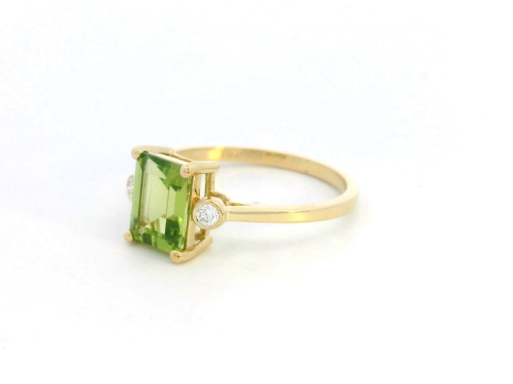 18K gold emerald-cut Peridot ring with 0.07ct diamond accents, featuring a vibrant 1.53ct Peridot centerpiece.