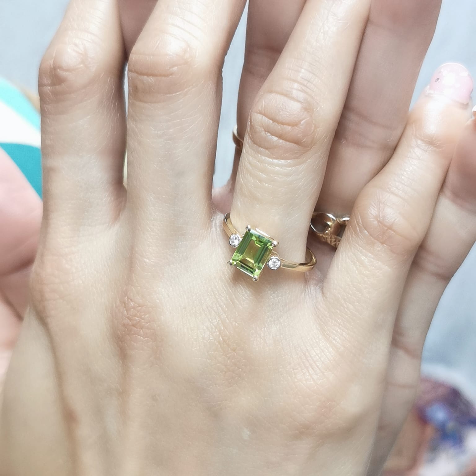 18K gold emerald-cut Peridot ring with 0.07ct diamond accents, featuring a vibrant 1.53ct Peridot centerpiece.