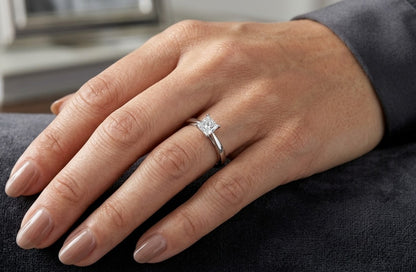 Princess cut diamond solitaire engagement ring in 18K white gold featuring a square diamond in a four-prong setting with a polished band.