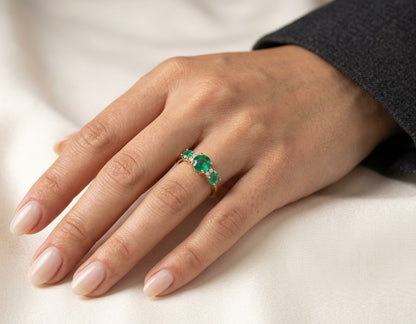 18K yellow gold three stone emerald ring with graduated round emeralds and diamond accents
