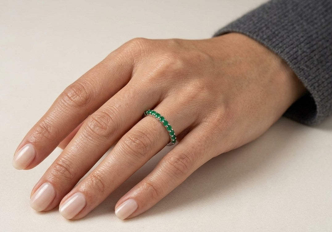 18K white gold half eternity ring with a single row of round green emeralds