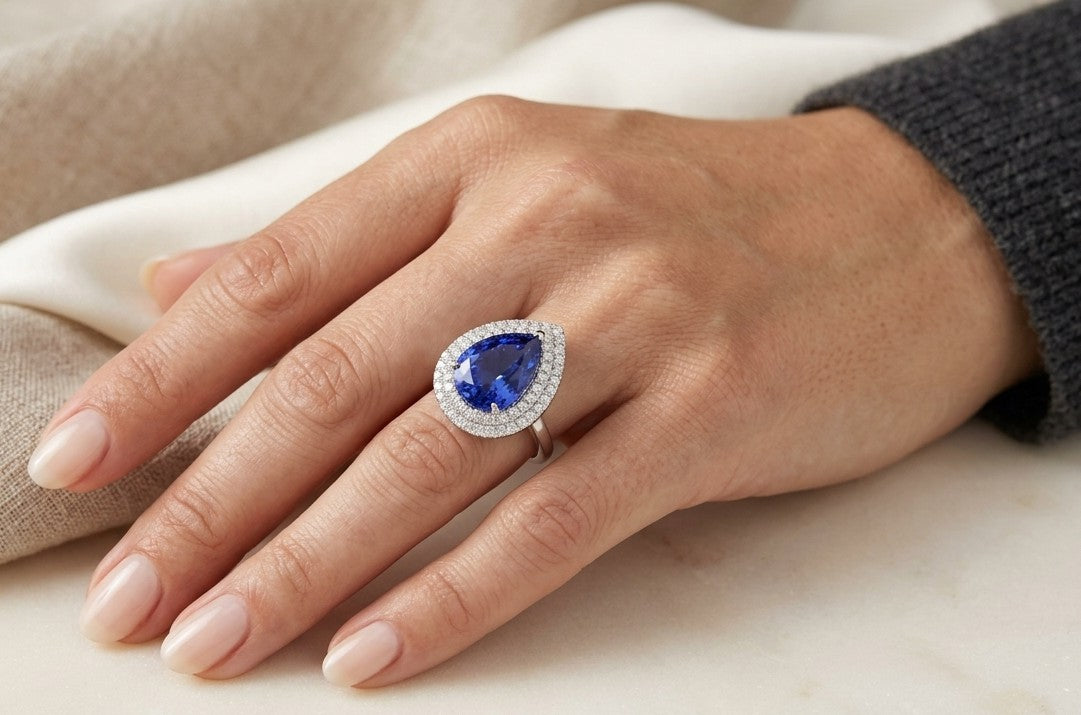 Tanzanite and diamond statement ring in 18K white gold featuring a large pear-shaped blue-violet tanzanite surrounded by a double halo of round diamonds.