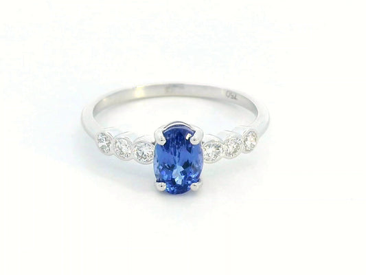 Oval tanzanite and diamond ring in 18K white gold with bezel-set side stones