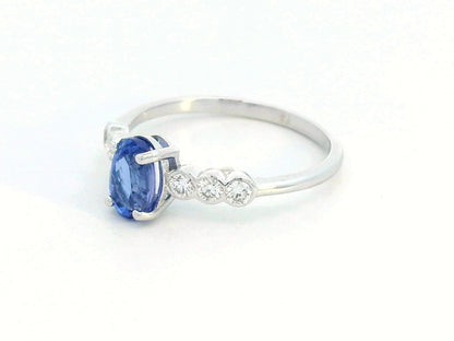 Oval tanzanite and diamond ring in 18K white gold with bezel-set side stones