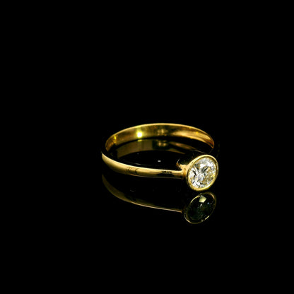 Round brilliant bezel set diamond engagement ring in 18K yellow gold with a slender solitaire band.