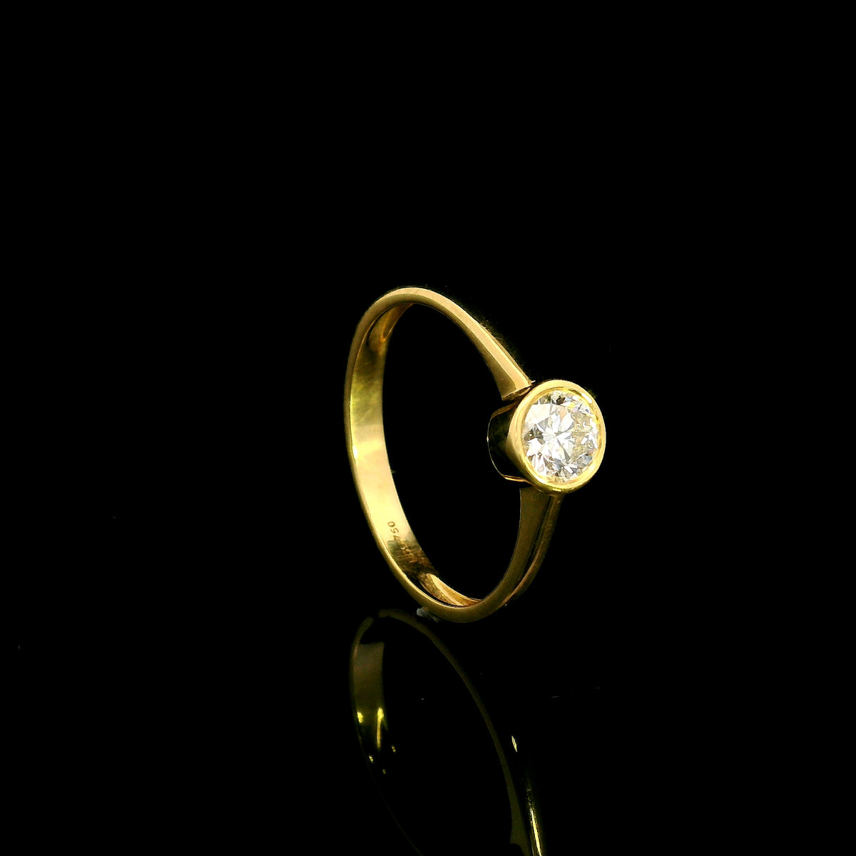 Round brilliant bezel set diamond engagement ring in 18K yellow gold with a slender solitaire band.