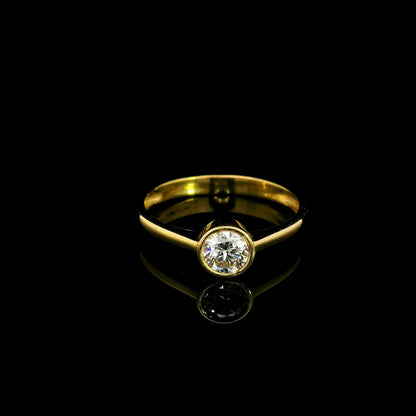 Round brilliant bezel set diamond engagement ring in 18K yellow gold with a slender solitaire band.