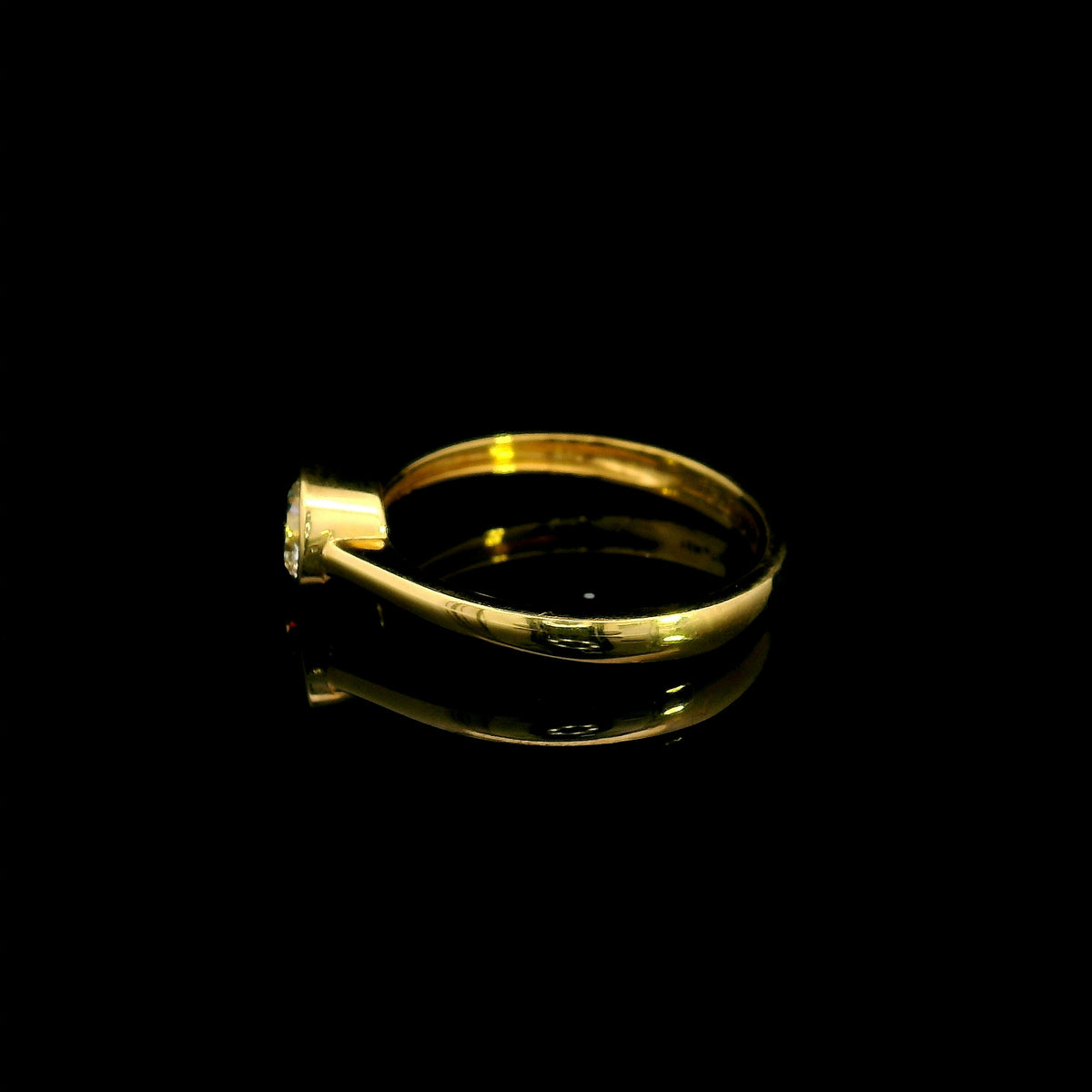 Round brilliant bezel set diamond engagement ring in 18K yellow gold with a slender solitaire band.