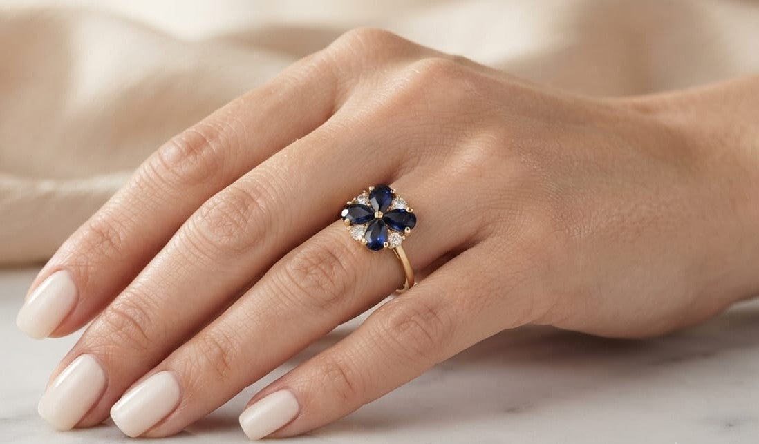 18K yellow gold flower ring featuring 1.79 carats of natural pear-shaped blue sapphires and 0.17 carat round brilliant diamonds in a floral cluster design.
