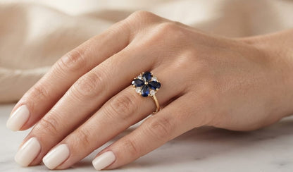 18K yellow gold flower ring featuring 1.79 carats of natural pear-shaped blue sapphires and 0.17 carat round brilliant diamonds in a floral cluster design.