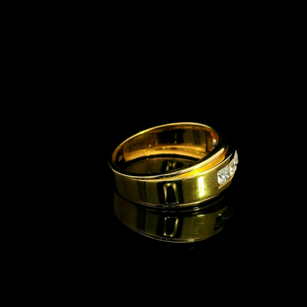 Yellow gold diamond band ring with channel set round diamonds and broad polished gold edges