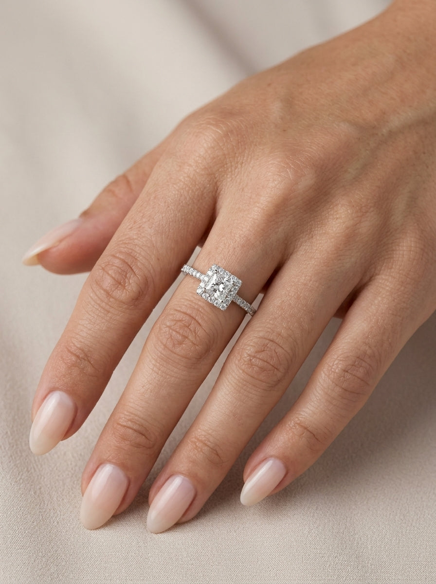 Princess cut diamond halo engagement ring in 18K white gold with a square diamond halo and diamond-set band.