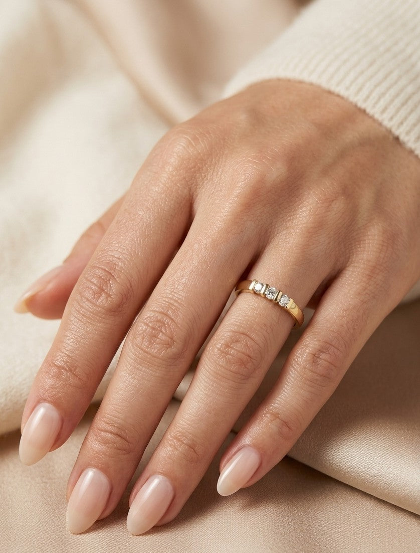 Three stone diamond ring in 18K yellow gold featuring three round brilliant diamonds set across a polished gold band.