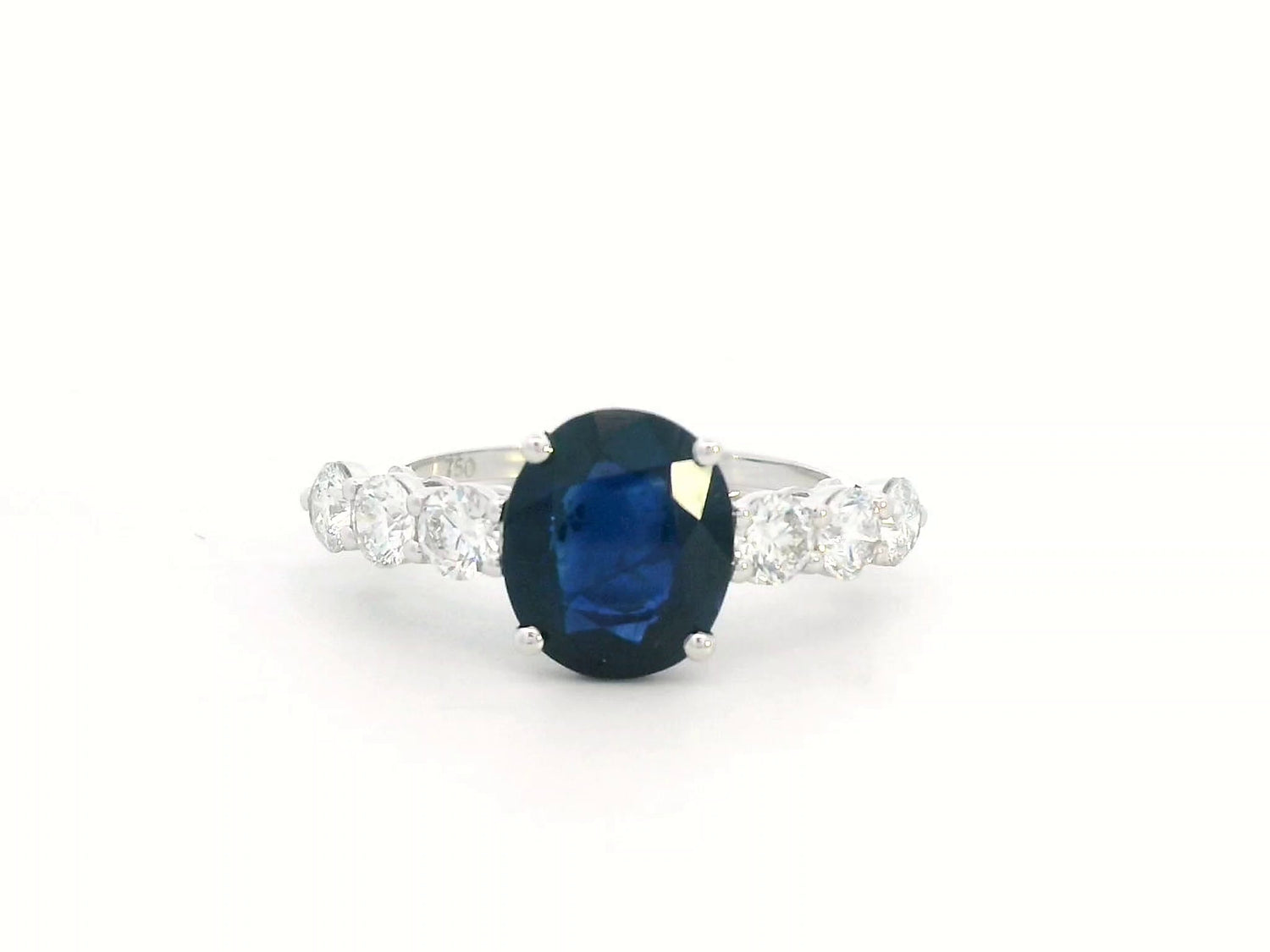 18K white gold ring with oval-cut 2.92ct blue sapphire and round cut diamonds on each side.