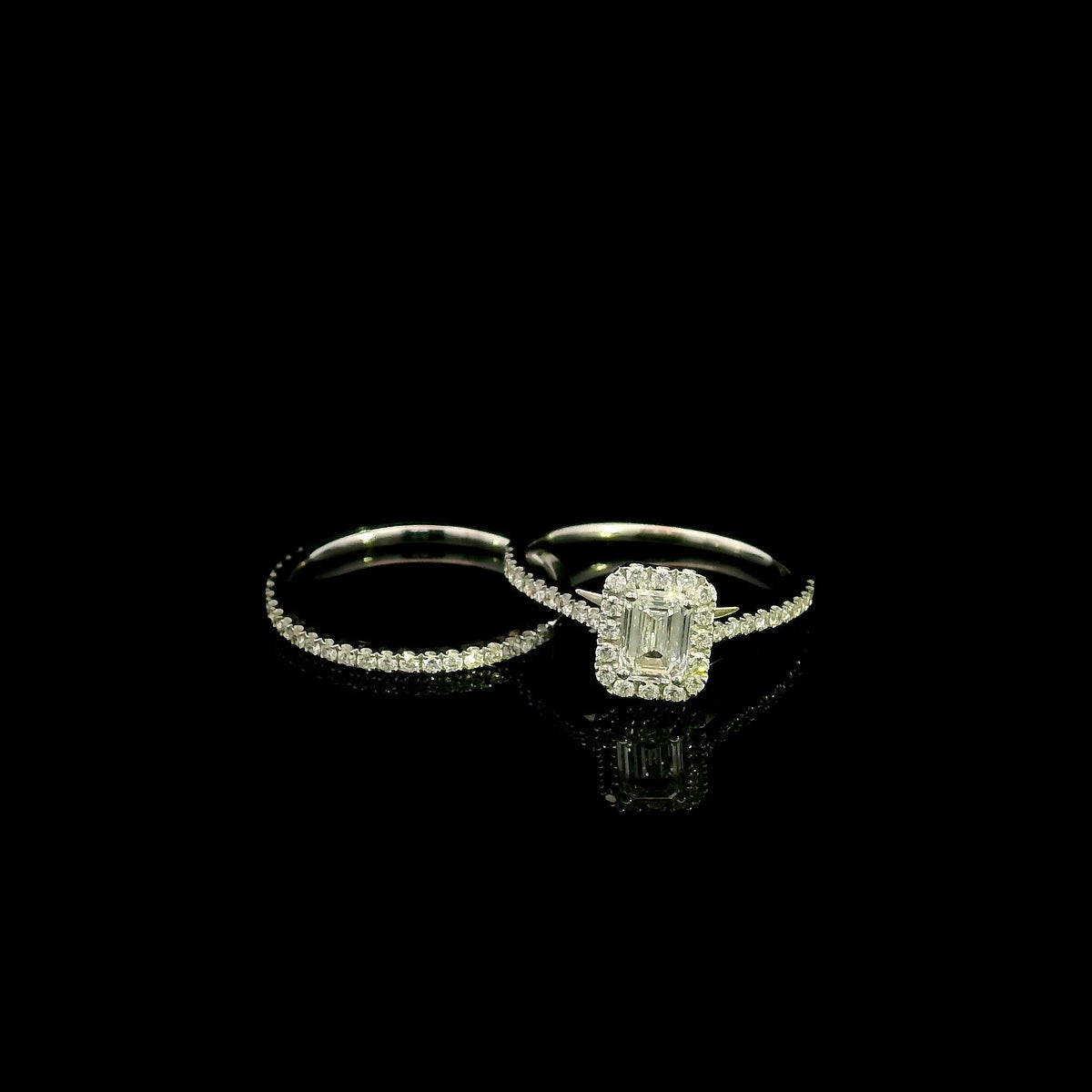 Emerald cut diamond halo bridal set in 18K white gold with a diamond engagement ring and matching wedding band.