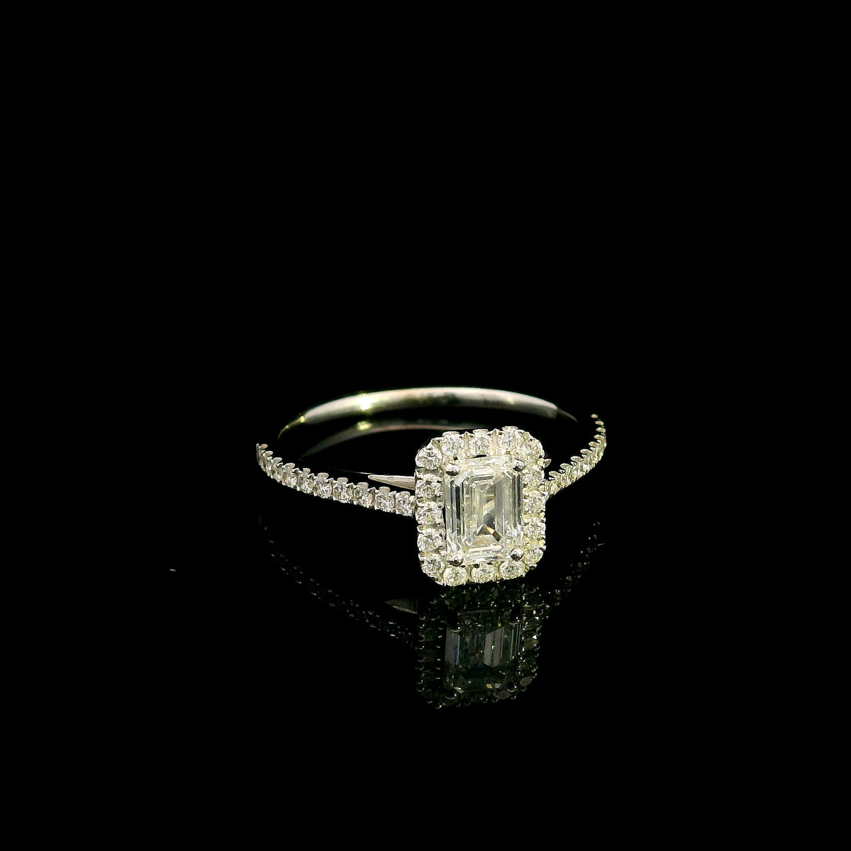 Emerald cut diamond halo bridal set in 18K white gold with a diamond engagement ring and matching wedding band.