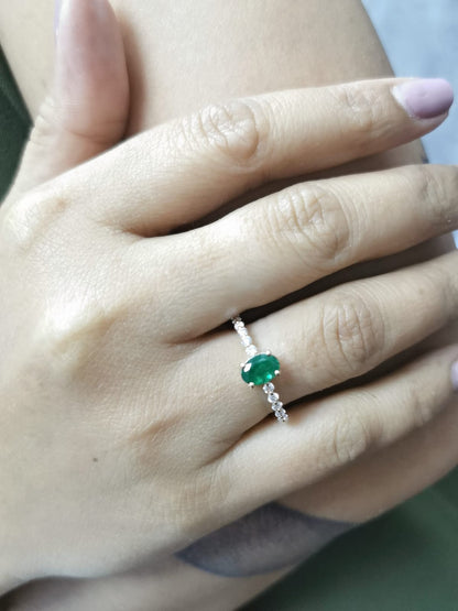 18K yellow gold ring with oval-cut emerald center and round diamond accents on the band

