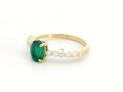 18K yellow gold ring with oval-cut emerald center and round diamond accents on the band

