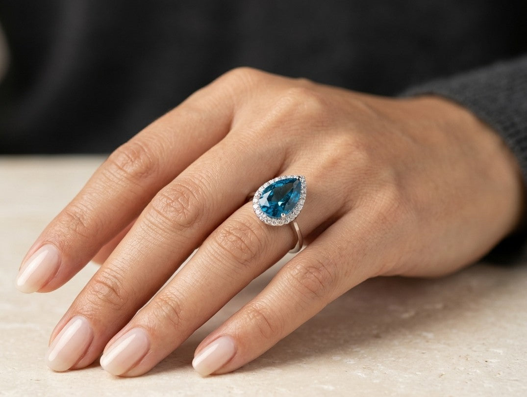 Pear shape London Blue Topaz halo ring in 18K white gold with natural diamond surround