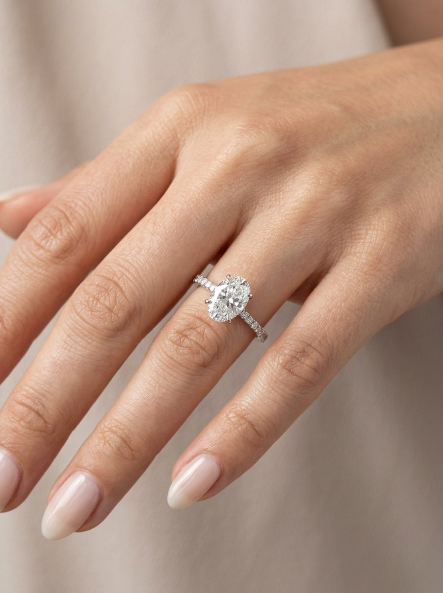Oval diamond engagement ring in 18K white gold with a four-prong centre diamond and round diamond-set band.