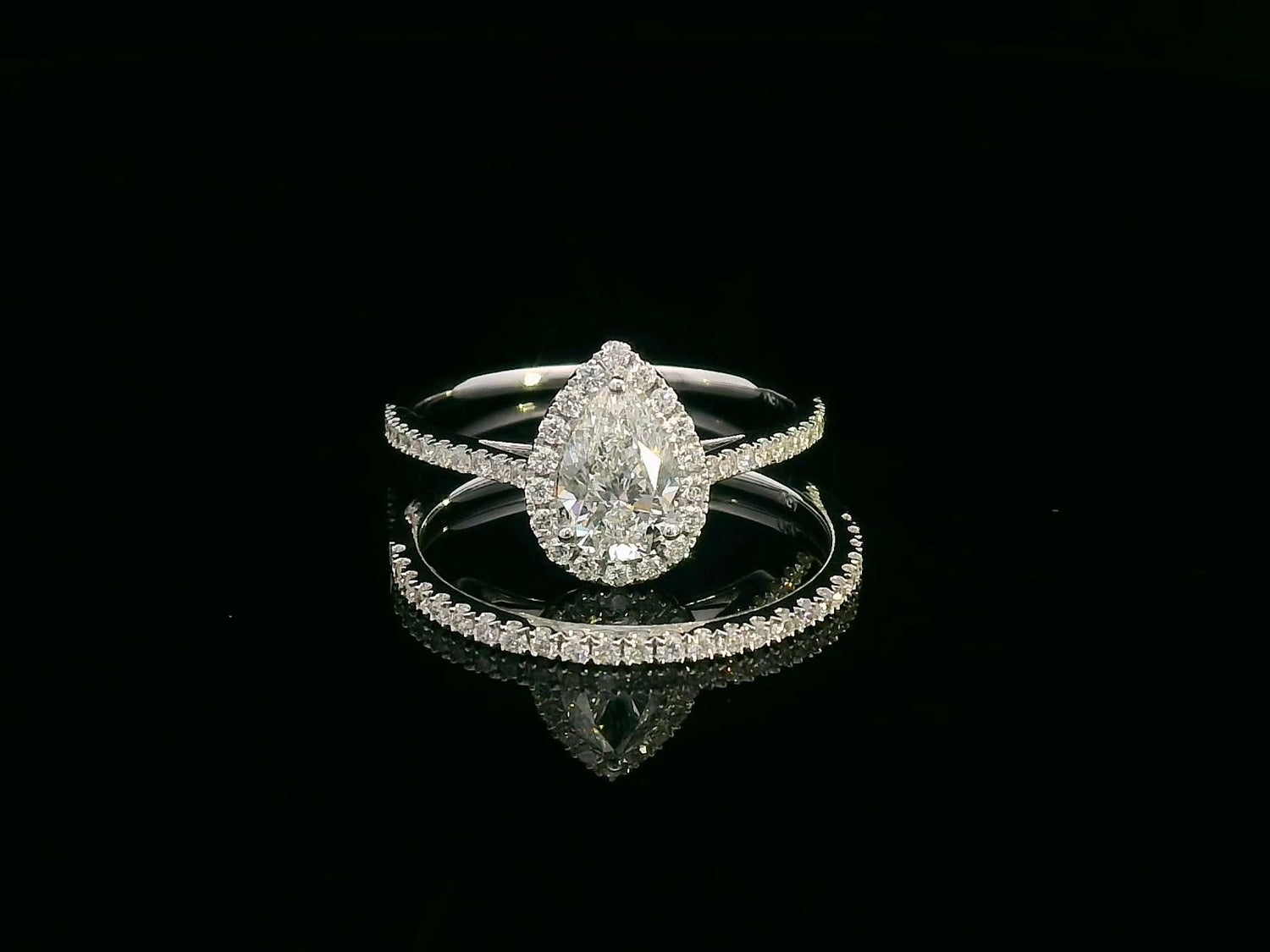 18K gold bridal ring set featuring a 0.91 carat pear-shaped diamond with halo and pavé-set accent diamonds on both engagement ring and matching wedding band