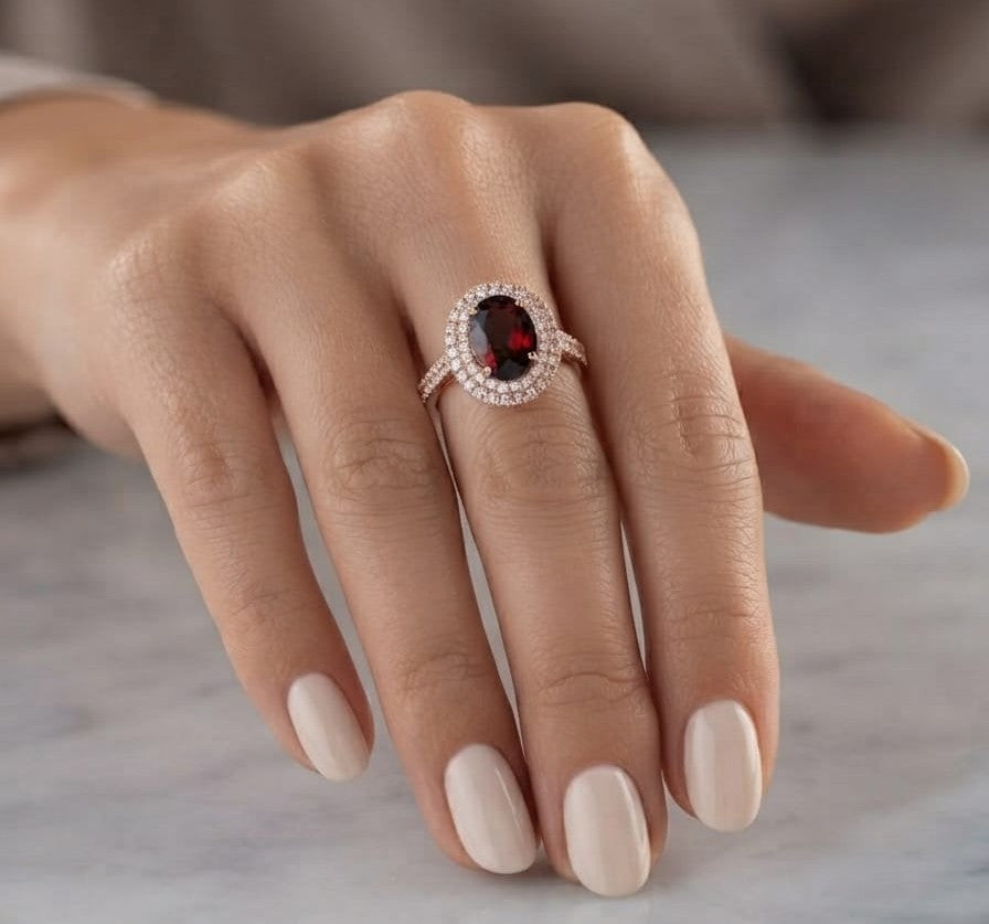 Oval garnet and diamond double halo ring in 18K rose gold with diamond-set shoulders.