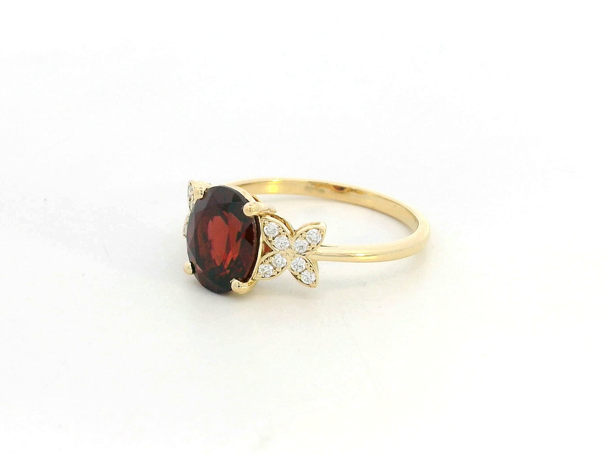 Side view showing four-prong garnet setting and delicate diamond clusters