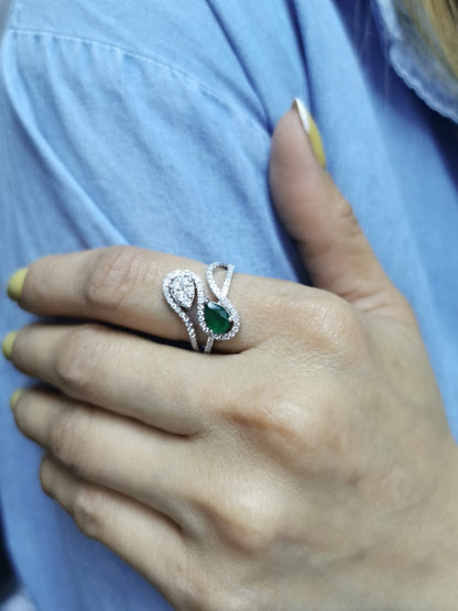 18k gold bypass ring with 0.59 ct pear-cut emerald, pear-shaped diamond cluster, and pavé diamonds, modern asymmetrical design.