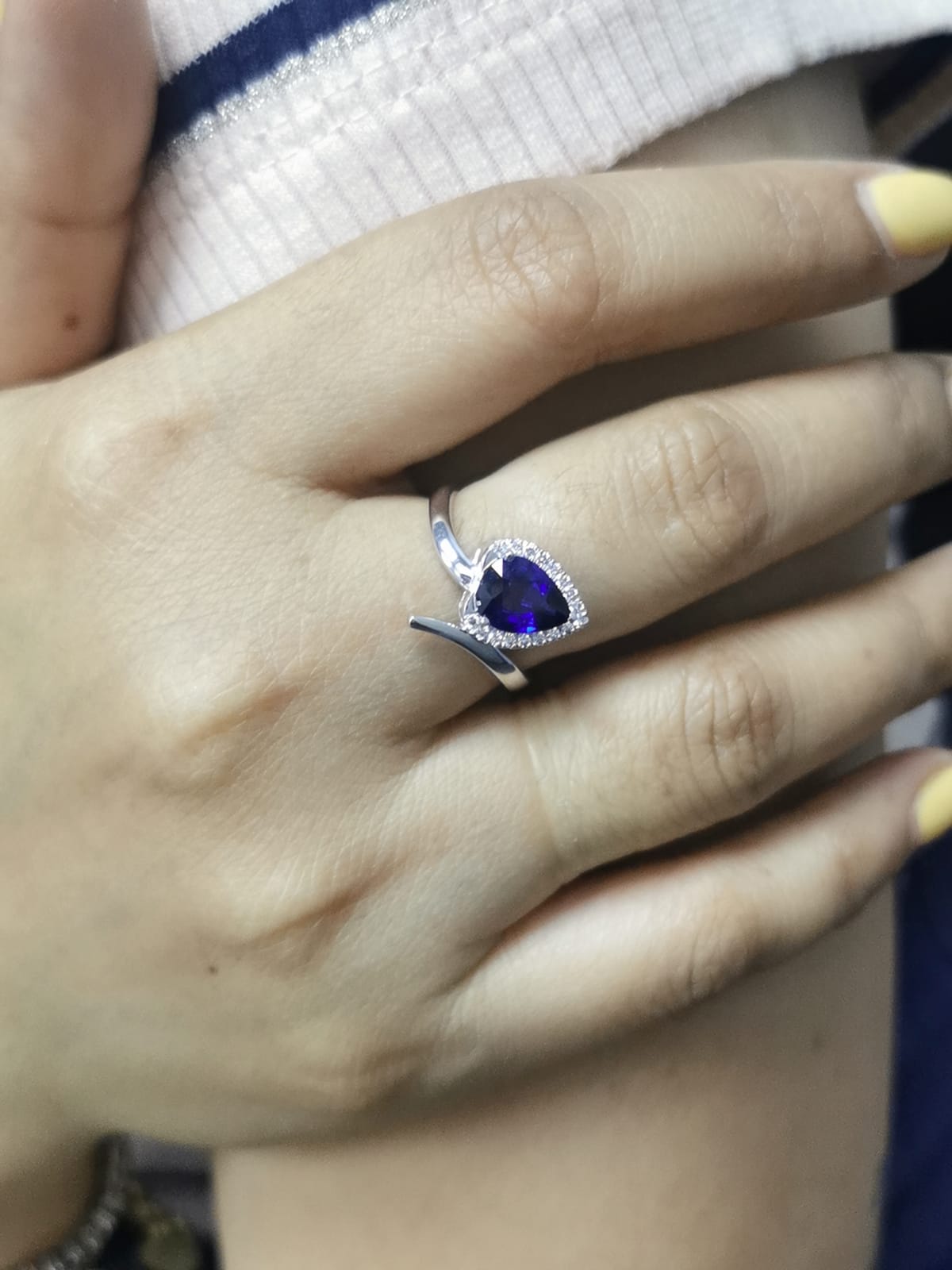 close-up highlighting halo and gemstone, ring on finger for scale