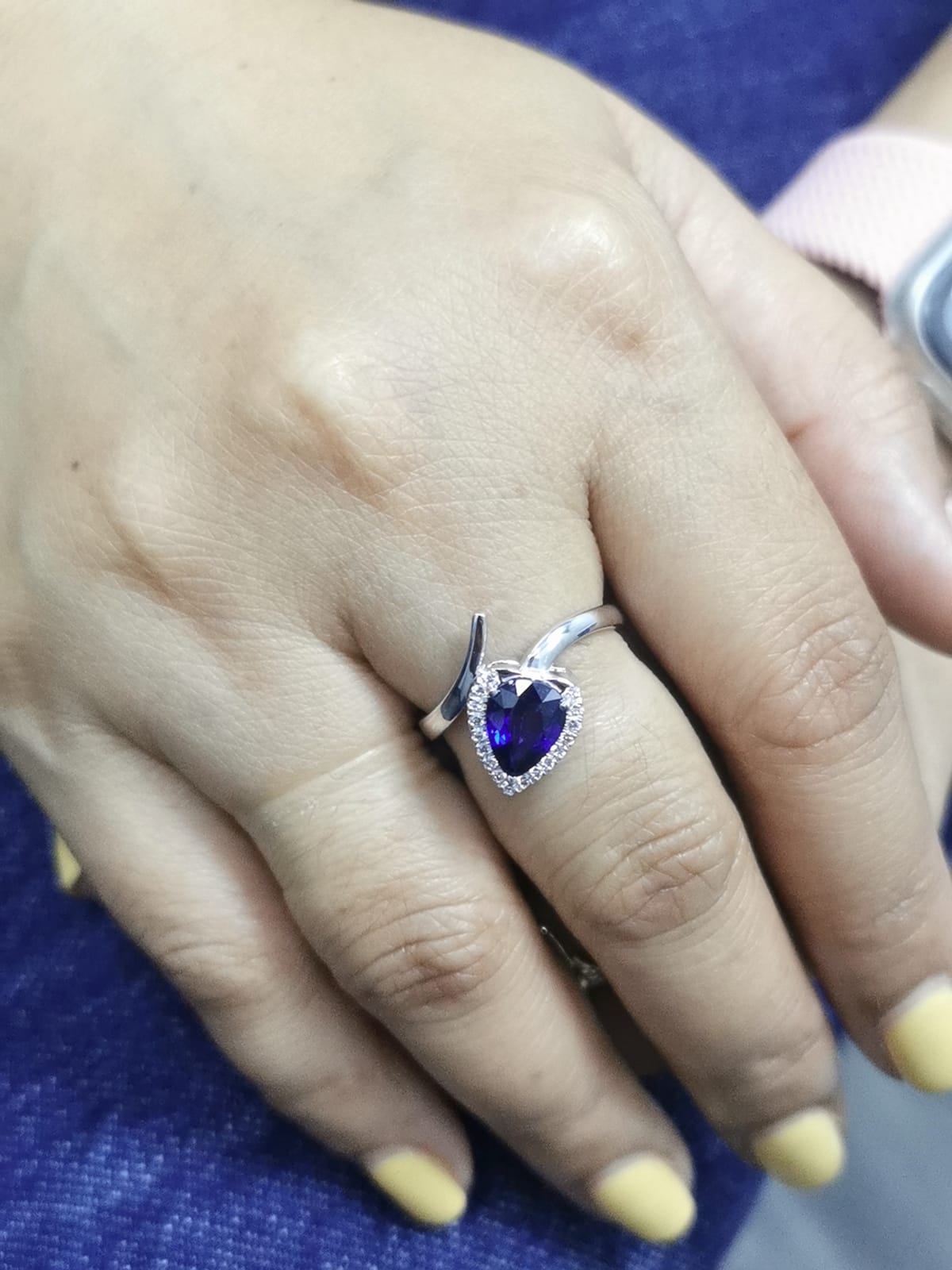 close-up highlighting halo and gemstone, ring on finger for scale