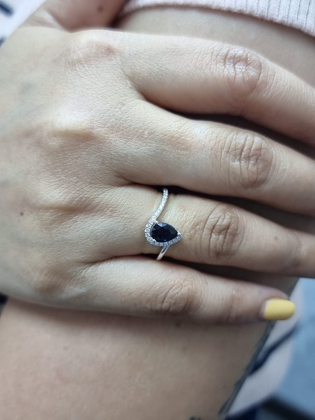 Ring on finger showcasing 0.90 ct blue sapphire, 0.14 ct diamond accents, and elegant bypass design