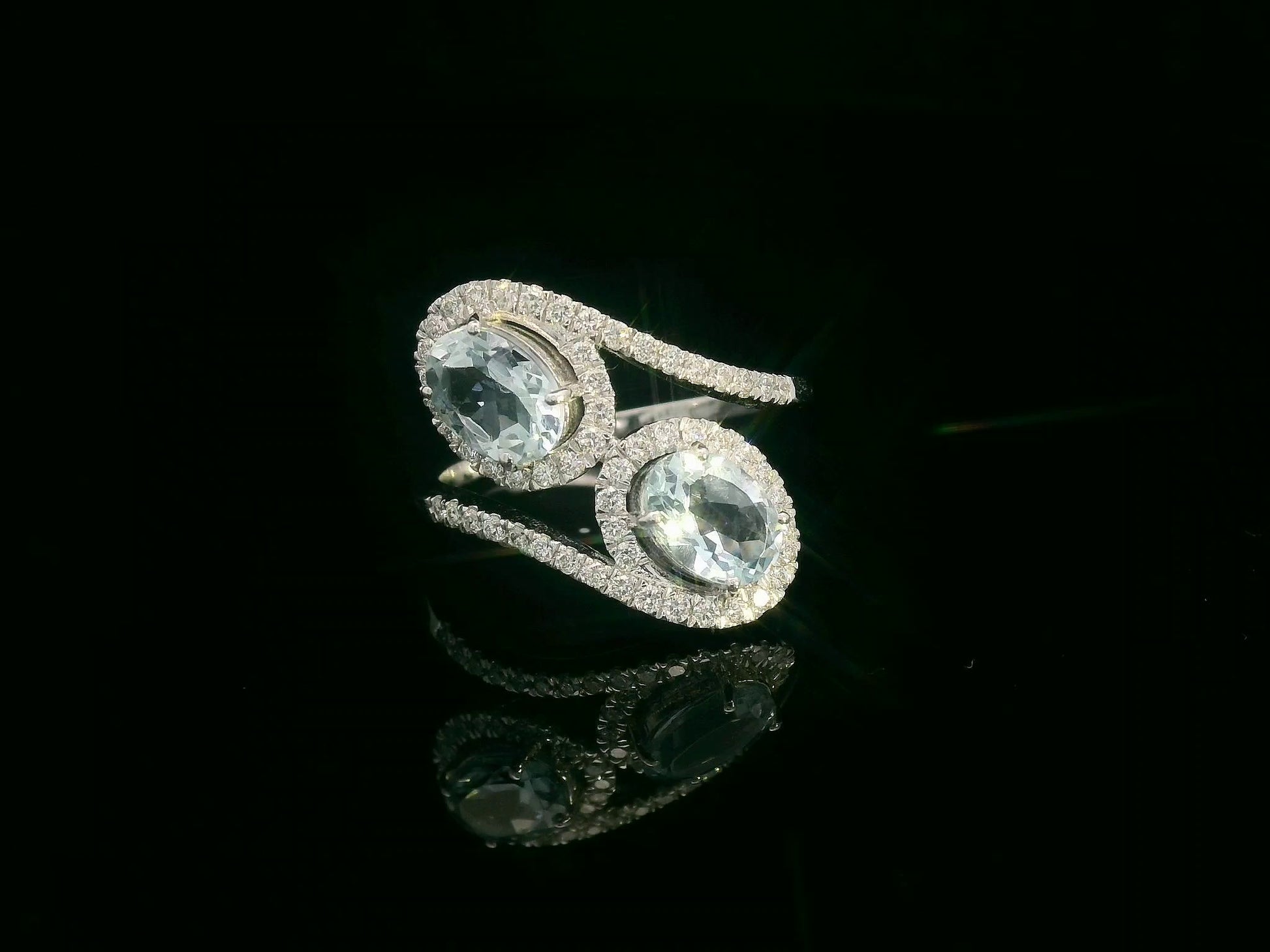 Front view of 18k white gold ring with two oval aquamarines and 0.39 ct diamond halos