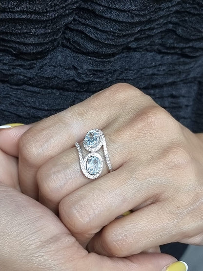Ring on finger showcasing twin aquamarines and elegant bypass band
