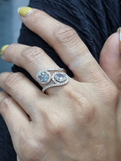 Ring on finger showcasing twin aquamarines and elegant bypass band