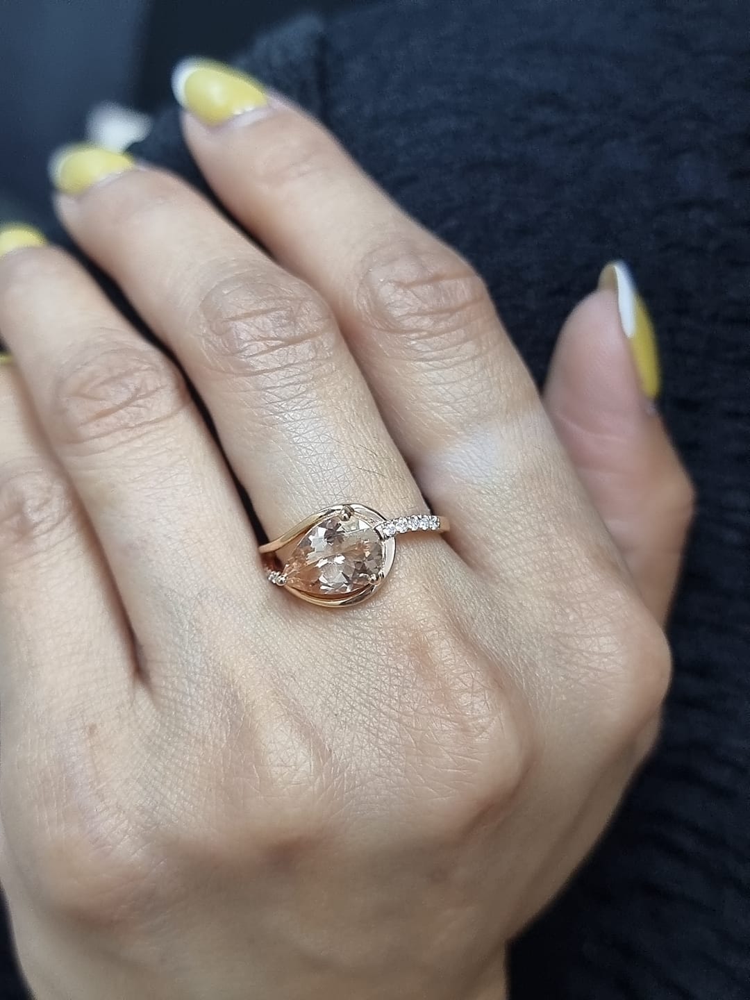Ring on finger showcasing morganite’s peach-pink hue and diamond sparkle