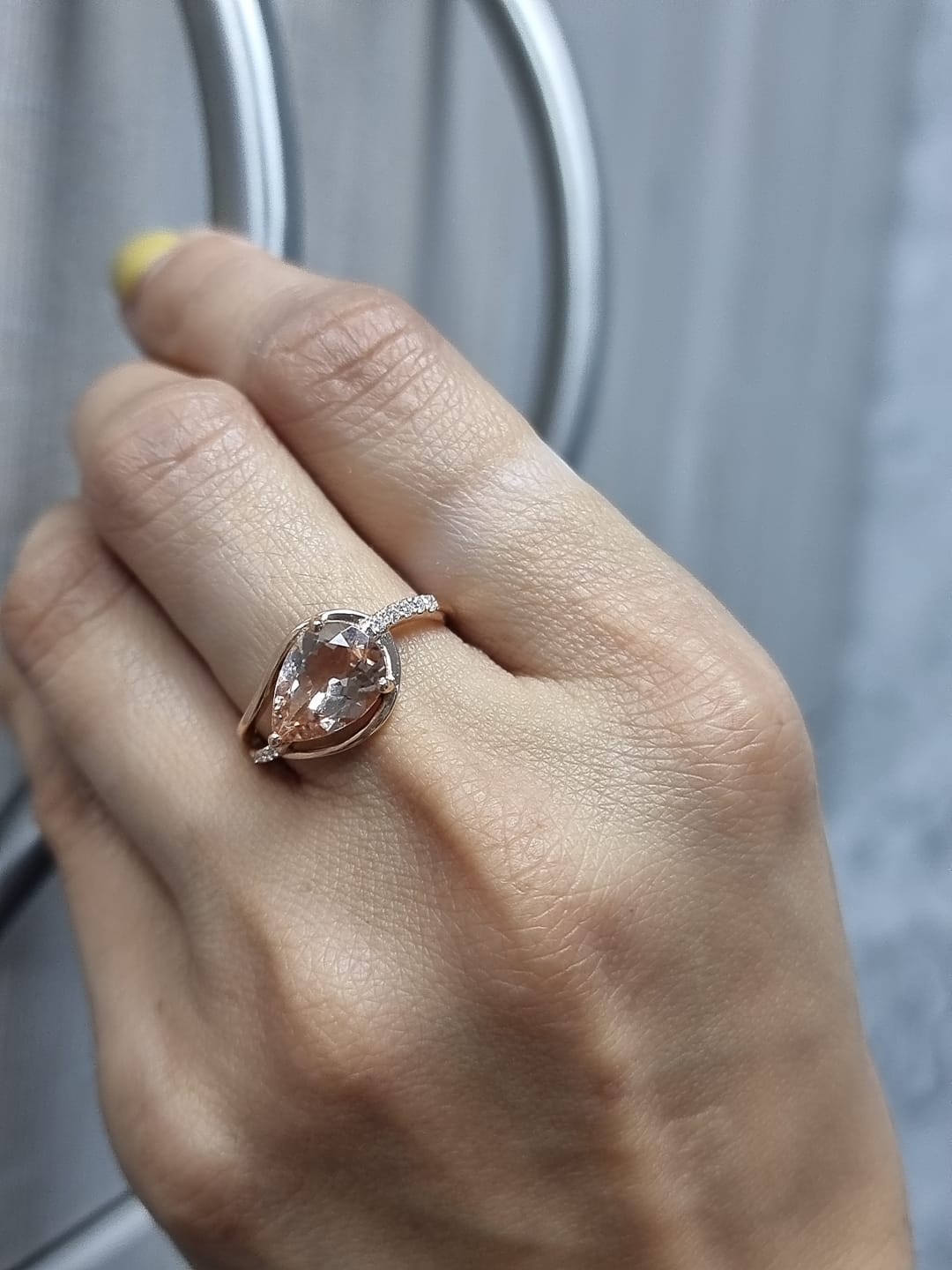 Ring on finger showcasing morganite’s peach-pink hue and diamond sparkle