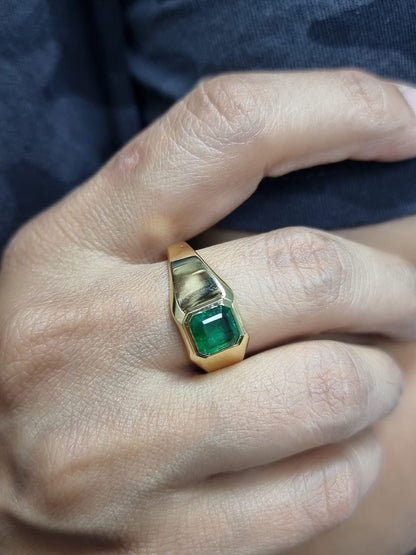 Ring on finger showcasing classic yellow gold and green emerald elegance