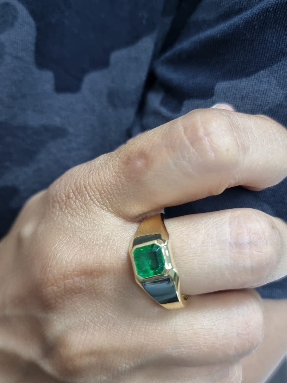 Ring on finger showcasing classic yellow gold and green emerald elegance