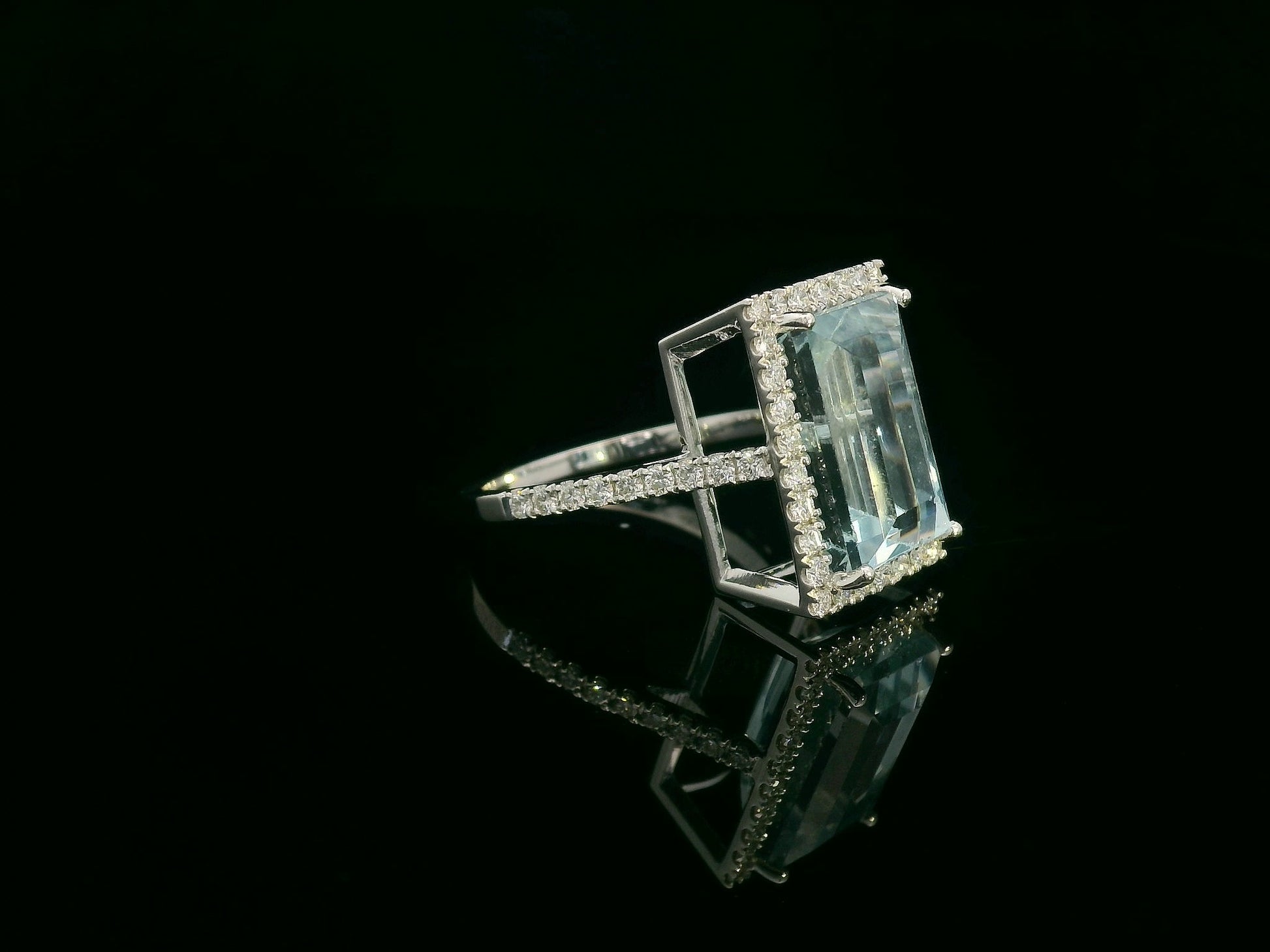 18K white gold aquamarine halo ring featuring a 7.66 carat emerald cut natural aquamarine surrounded by 0.64 carat round brilliant diamonds with a diamond-set band.