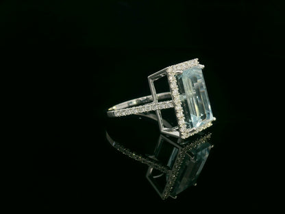 18K white gold aquamarine halo ring featuring a 7.66 carat emerald cut natural aquamarine surrounded by 0.64 carat round brilliant diamonds with a diamond-set band.