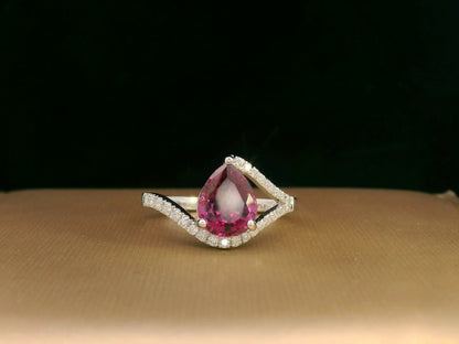 18K white gold rhodolite garnet and diamond wave ring featuring a 1.97ct pear-cut garnet framed by 0.23ct pavé diamonds in an elegant wave design.