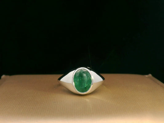 18K white gold men’s signet ring featuring a 1.80ct oval-cut emerald in a sleek bezel setting with a solid tapered band.
