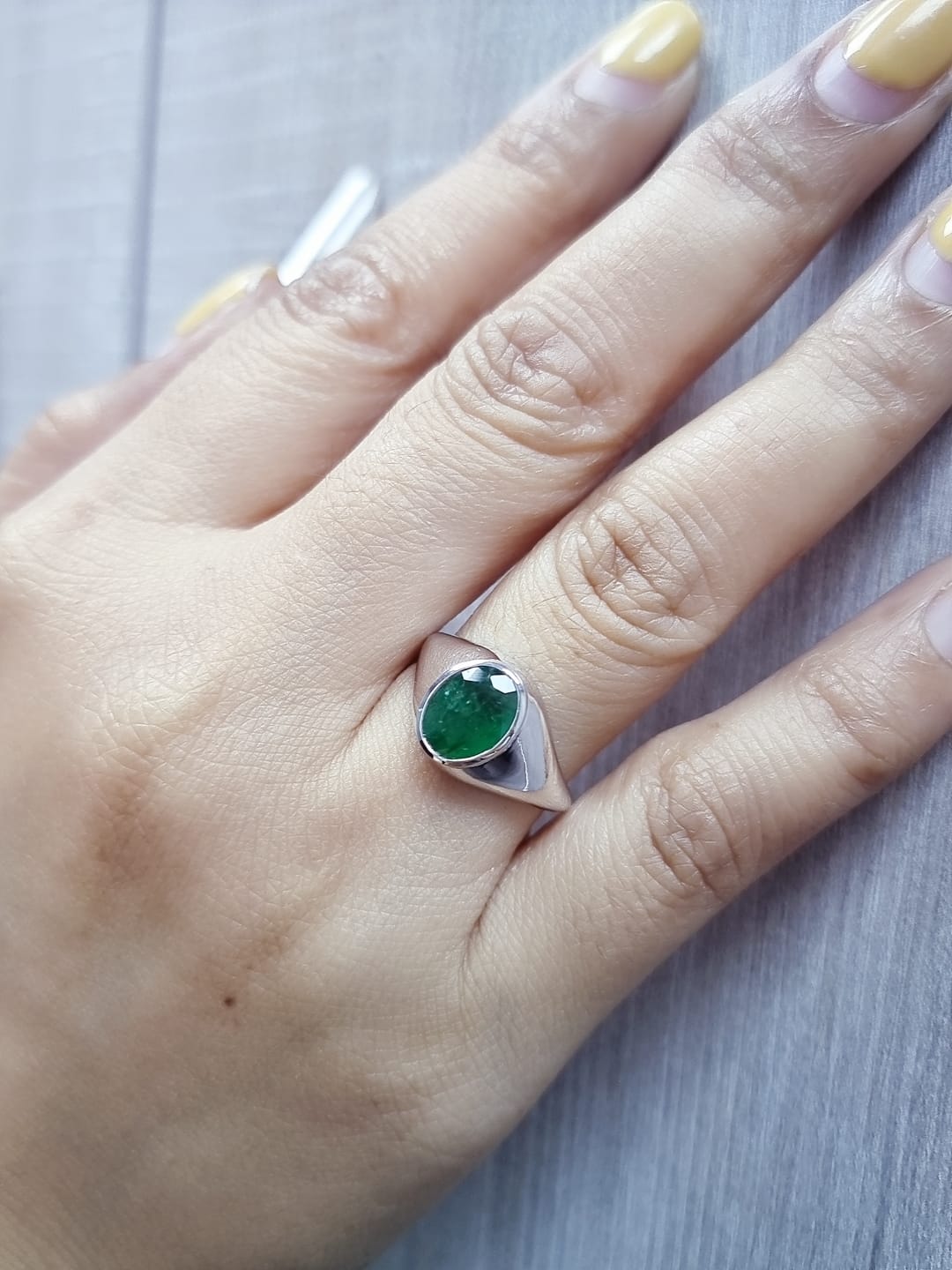 18K white gold men’s signet ring featuring a 1.80ct oval-cut emerald in a sleek bezel setting with a solid tapered band.