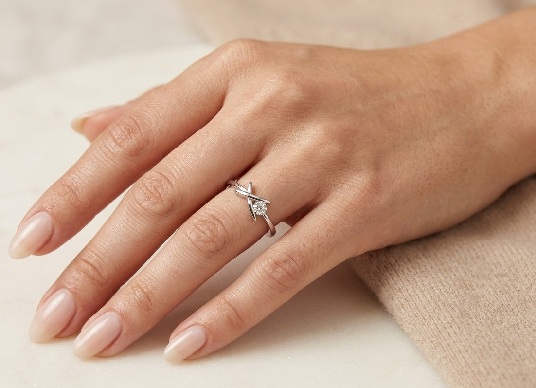 Round brilliant diamond solitaire ring in 18K white gold with sculptural crossover setting