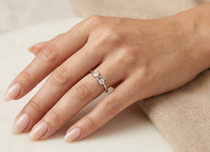 Round brilliant diamond solitaire ring in 18K white gold with sculptural crossover setting