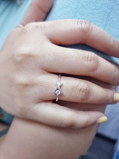 18K white gold ring featuring a 0.12 ct round diamond in a modern tension “X” design, with certificate of authenticity.