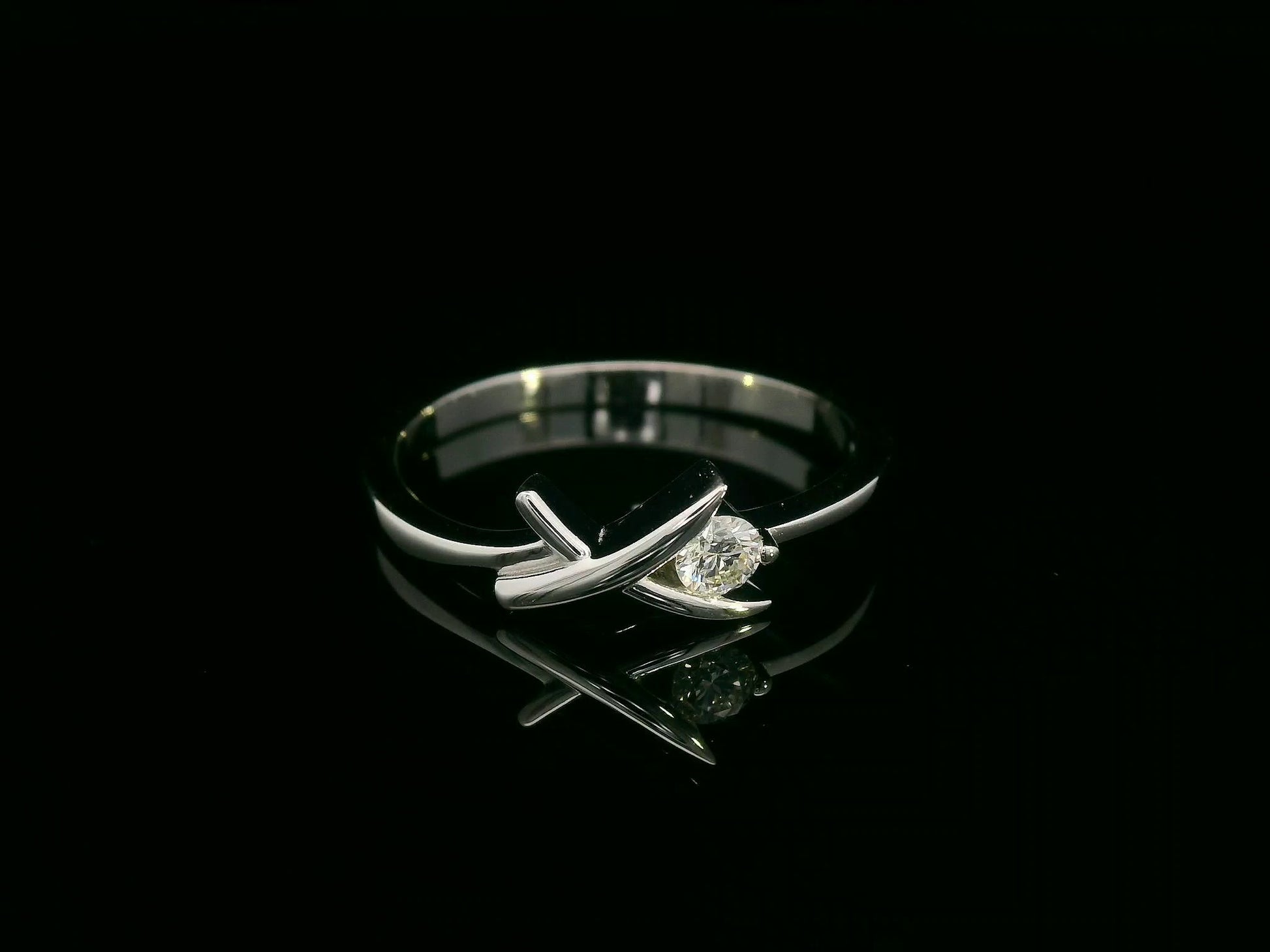 18K white gold ring featuring a 0.12 ct round diamond in a modern tension “X” design, with certificate of authenticity.